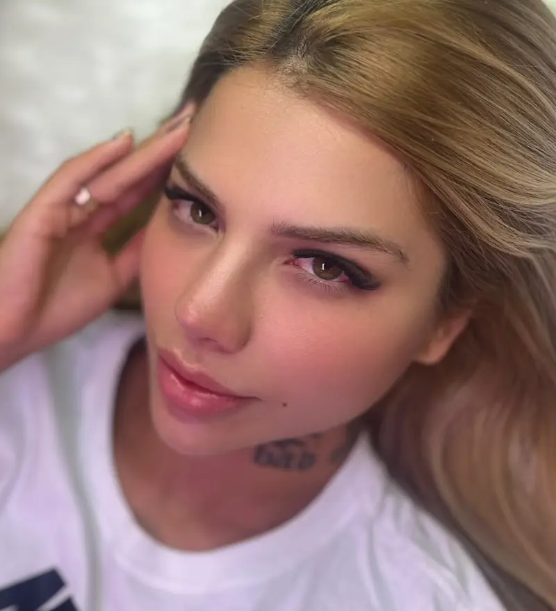 Modelo loira com as mãos no rosto, cílios e sobrancelhas — trabalho do Deluca Studio Beauty, Balneário Camboriú